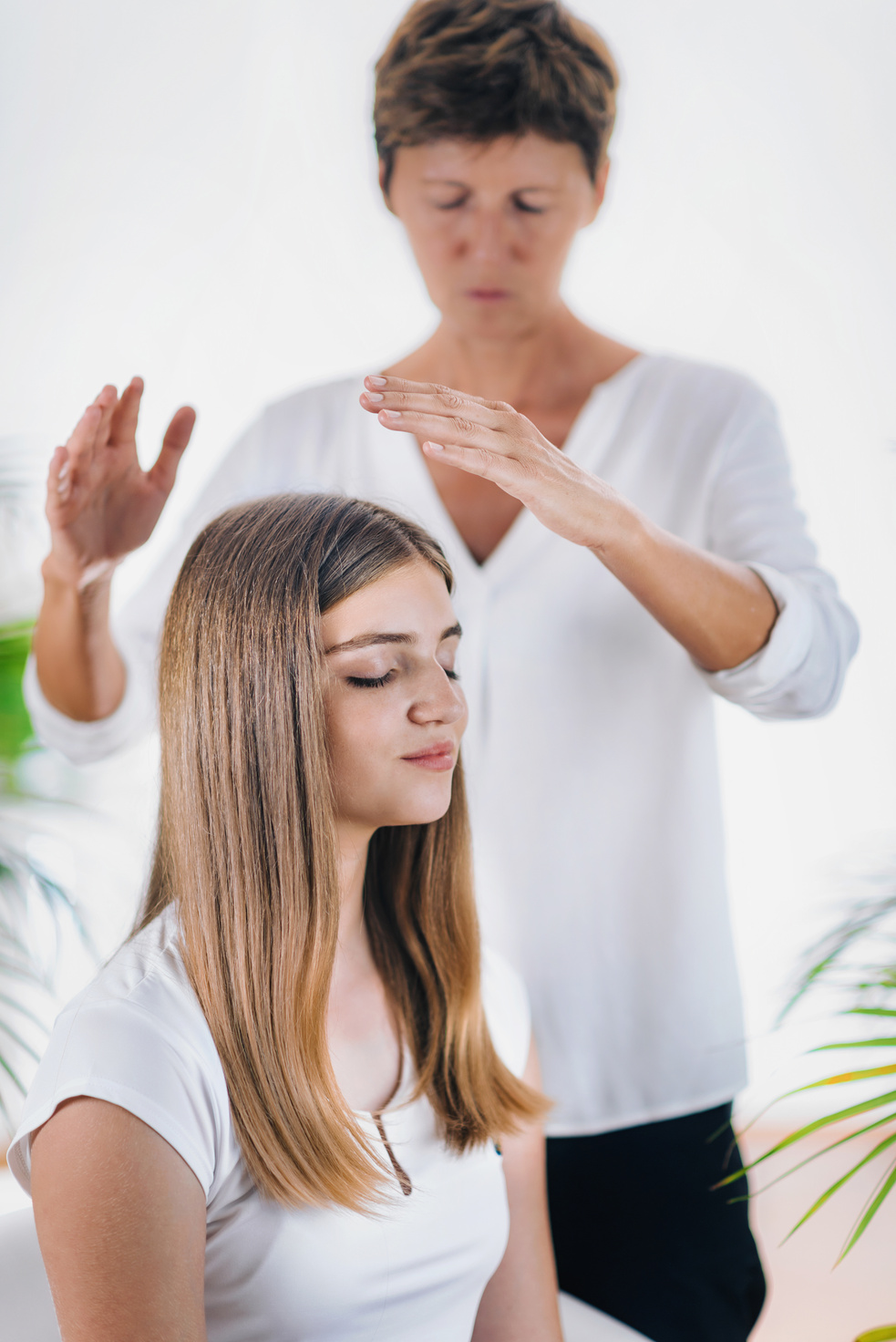 Midsection Of Therapist Giving Reiki Treatment To Teenage Girl On Head At Spa